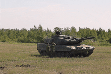 a military tank is parked in a grassy field with two men standing next to it