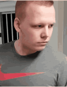 a man wearing a grey shirt with a red nike logo on the front