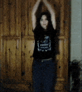 a woman wearing a fearless shirt is dancing in front of a wooden cabinet