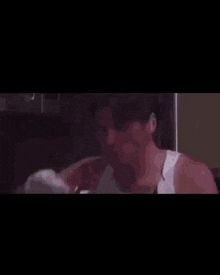 a shirtless man is standing in front of a refrigerator in a kitchen .