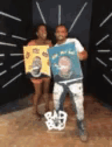 a man and a woman are standing next to each other holding paintings of themselves .