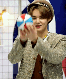 a man wearing a hat and a jacket is holding a beach ball