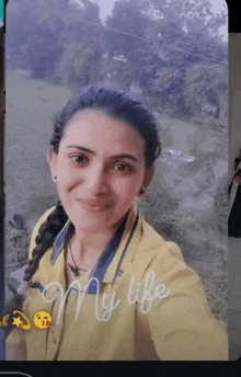 a woman in a yellow shirt is taking a selfie with the words " my life " written on the bottom