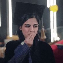 a woman in a graduation cap and gown covering her mouth
