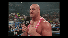 a wrestler is talking into a microphone with a crowd behind him