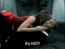 a woman in a red dress is laying on top of a man in a suit and the words it 's hot are visible