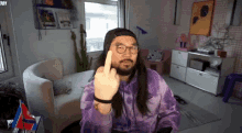 a man with long hair and a beard is giving the middle finger .