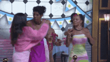 a group of women are standing next to each other in a room holding drinks .