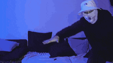 a man wearing a mask and a hat is standing on a bed