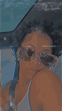 a woman wearing sunglasses is taking a selfie in the back seat of a car