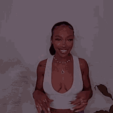 a woman wearing a white tank top and a necklace that says ' u ' on it