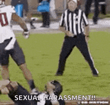 a referee is standing in front of a football player who is laying on the field .