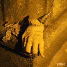a hand with stitches and a party hat is hanging from a wall with the netflix logo in the corner