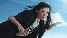 a woman in a plaid jacket and a white shirt with the word air on it is flying through the air