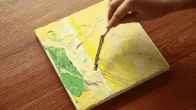 a person is painting a yellow and green picture