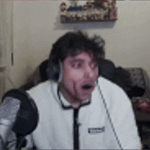 a man wearing headphones is sitting in front of a microphone and making a funny face .