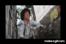 a man is standing next to a wall with a sign on it that says make a gif.com