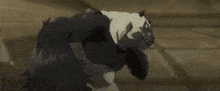 a black and white cartoon panda bear with a purple eye is running across a floor .