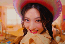 a woman wearing a cowboy hat and pigtails looks at the camera