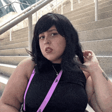 a woman wearing a black top and a purple lanyard that says ' la ' on it