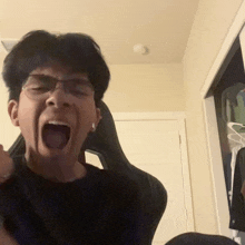 a man wearing glasses and a black shirt is screaming with his mouth open