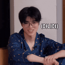 a young man wearing glasses and a blue pajama shirt is smiling with the words ( oliof ) below him