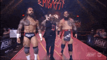 three wrestlers are walking down a red carpet .