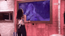 a woman is standing in front of a large television .