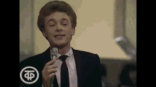 a man in a suit and tie singing into a microphone