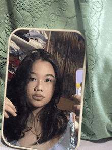 a woman taking a selfie in a mirror with a green curtain behind her