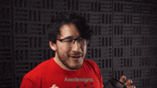 a man in a red shirt is holding a gun in front of a wall that says " the boys "