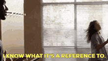 a man and a woman are dancing in front of a window and the woman is saying i know what it 's a reference to