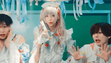 a girl with white hair and red ribbons is holding a wii controller