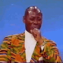 a man in a colorful suit is holding his hand to his mouth