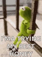 kermit the frog is sitting on a railing and holding onto a railing .