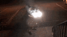 a person is standing on a sidewalk in front of a car with a firework display in the background .