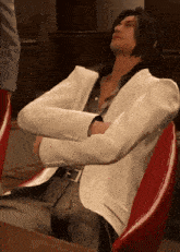 a man in a white suit is sitting in a red chair