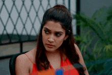a woman in a red top is sitting in a chair looking at something