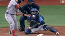 a baseball player is swinging at a ball while a catcher tries to catch it .