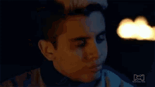 a close up of a man 's face in a dark room with a candle in the background .