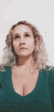 a woman with blonde hair and a green shirt looks up