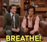 two men are sitting on a couch and one of them is saying breathe !