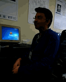a man sits in front of a computer with a sign that says vit
