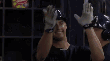 a brewers baseball player stands in the dugout with his arms outstretched