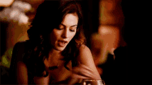 a woman is sitting at a table with a glass of wine and a necklace .