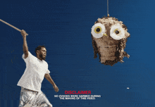 a man in silver shorts is holding an owl piñata with a stick