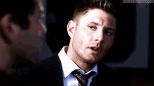 a man in a suit and tie talking to another man