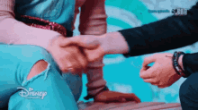 a man and a woman are shaking hands with a disney channel logo in the background
