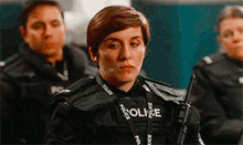 a woman in a police uniform is holding a walkie talkie and looking at the camera .