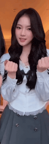 a girl with long black hair is wearing a white shirt and a green skirt